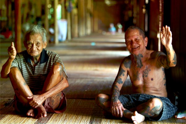 Iban men wave in Batang Ai longhouse - Discover Sarawak